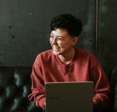 Mulher sorrindo olhando para o lado com notebook no colo